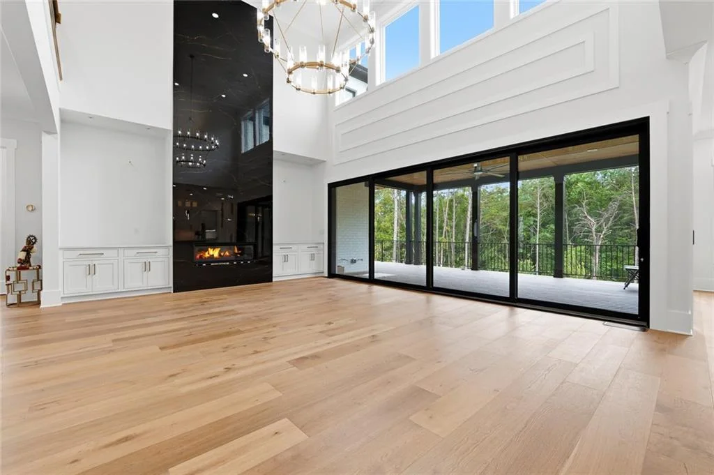 Listing photo showing a tall living room, fireplace and broad glass doors